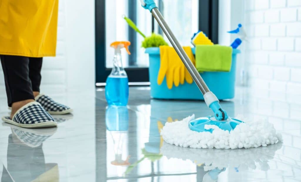 a person cleaning floor with a floor brush in his hand